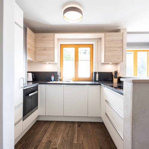 Küche mit weißen Schränken und dunkler Arbeitsplatte in Ferienwohnung in Garmisch-Partenkirchen