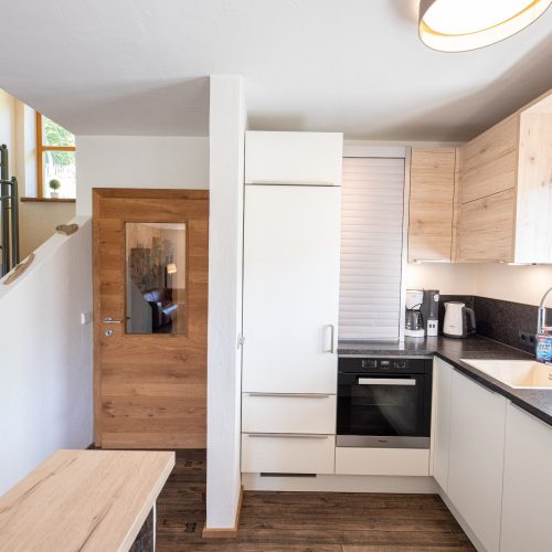 Küche mit dunkler Arbeitsplatte und einer Bank in Ferienwohnung in Garmisch-Partenkirchen