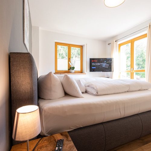 Bett mit Nachtschränkchen und Lampe in Ferienwohnung in Garmisch-Partenkirchen