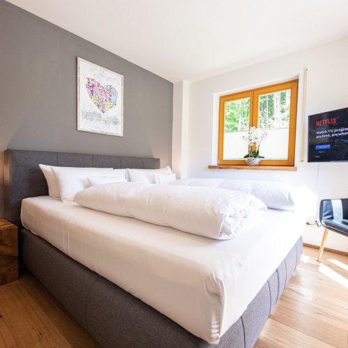 Doppelbett mit Fernseher und Stuhl in Ferienwohnung in Garmisch-Partenkirchen