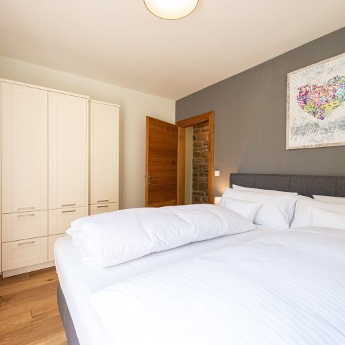 Doppelbett mit einem Kleiderschrank und einem Bild mit Herzform in Ferienwohnung in Garmisch-Partenkirchen