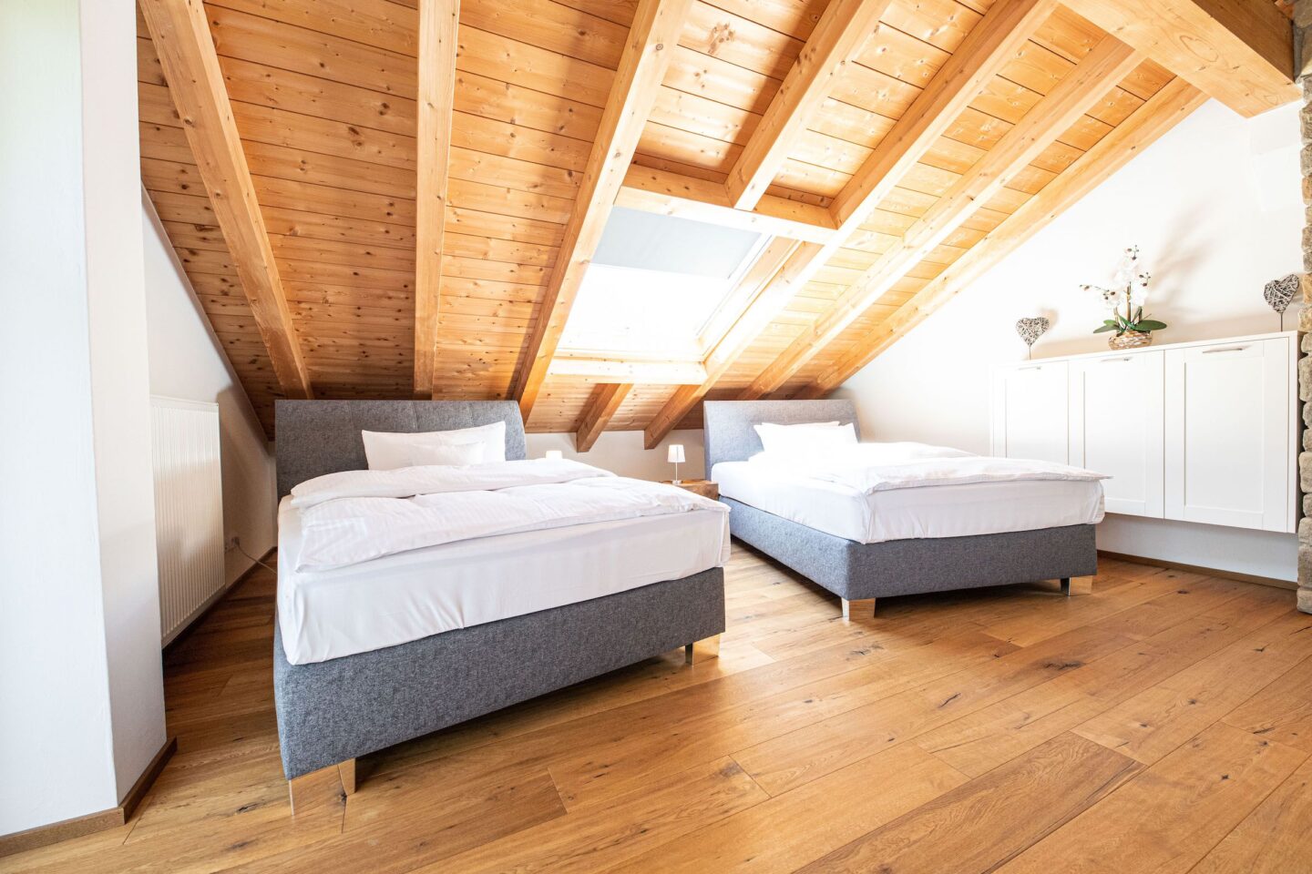 Zwei große Einzel betten in grau unter einer Dachschräge in Ferienwohnung in Garmisch-Partenkirchen