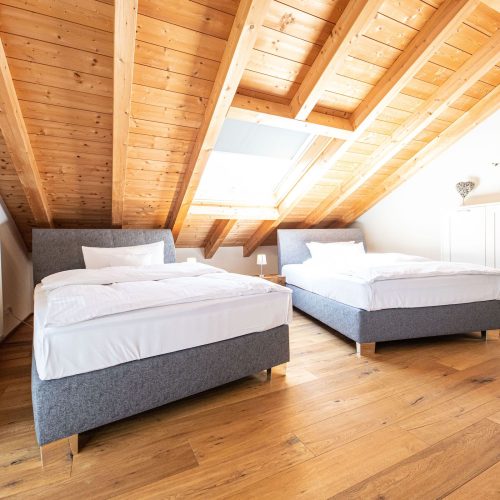 Zwei große Einzel betten in grau unter einer Dachschräge in Ferienwohnung in Garmisch-Partenkirchen