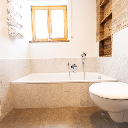 Badezimmer mit Badewanne und Regalen in Ferienwohnung in Garmisch-Partenkirchen