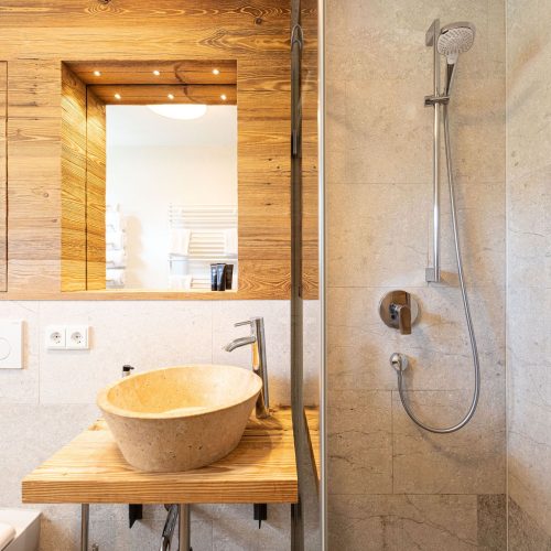 Badezimmer mit Dusche und Waschbecken mit Spiegel in Ferienwohnung in Garmisch-Partenkirchen