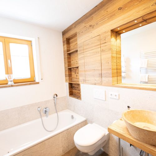 Badezimmer mit Badewanne und Waschbecken mit Spiegel in Ferienwohnung in Garmisch-Partenkirchen