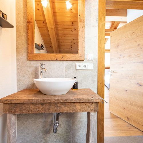 Holztisch mit Waschbecken und einem Spiegel mit Holzrahmen in Ferienwohnung in Garmisch-Partenkirchen