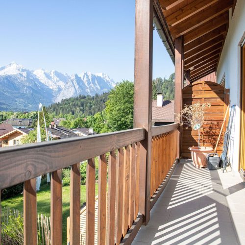 Balkon mit hellgrauen Fliesen und einem Holzzaun in Ferienwohnung in Garmisch-Partenkirchen