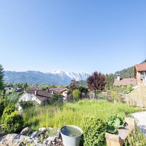 Ausblick auf den Außenbereich mit einer Terrasse und einem Rasenstück in Ferienwohnung in Garmisch-Partenkirchen