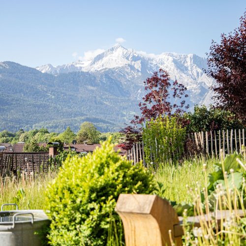 Ausblick auf den grünen Garten und die Alpen in Ferienwohnung in Garmisch-Partenkirchen