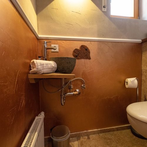 Badezimmer mit Fliesen und braunen Wänden und einem kleinen Waschbecken in Ferienwohnung in Garmisch-Partenkirchen
