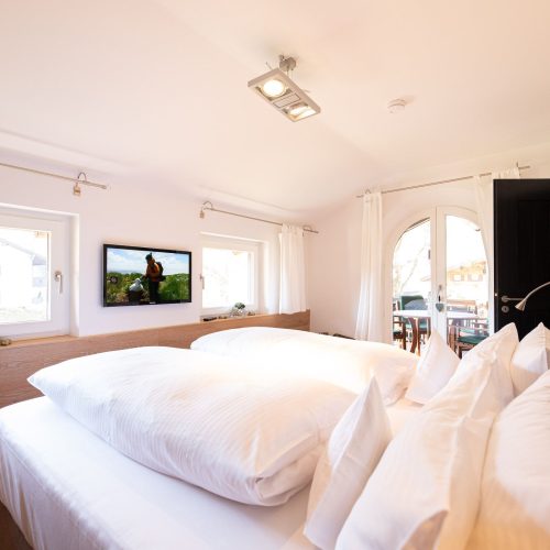 Doppelbett mit Fernseher und Fenster in Ferienwohnung in Garmisch-Partenkirchen