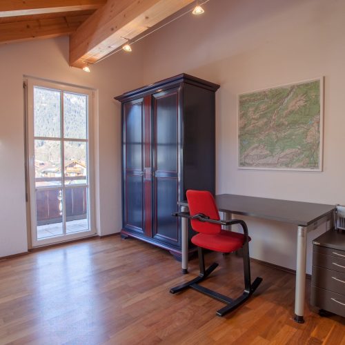 Schreibtisch mit rotem Stuhl in Ferienwohnung in Garmisch-Partenkirchen