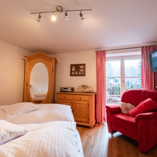 Doppelbett und roter Sessel in Ferienwohnung in Garmisch-Partenkirchen