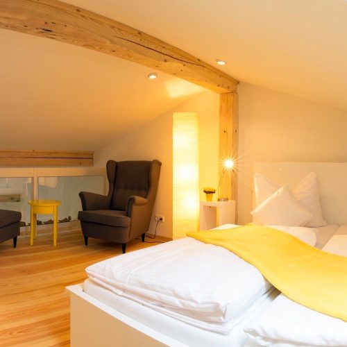 Doppelbett mit Sessel und Tisch in Ferienwohnung in Garmisch-Partenkirchen