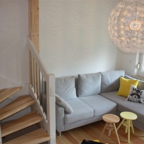 Wohnbereich mit grauem Sofa und Hockern in Ferienwohnung in Garmisch-Partenkirchen