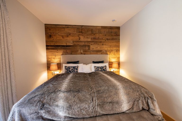 Doppelbett mit Holzwand in Ferienwohnung in Garmisch-Partenkirchen
