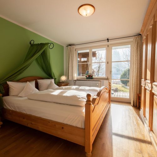 Doppelbett und grüne Wand in Ferienwohnung in Garmisch-Partenkirchen