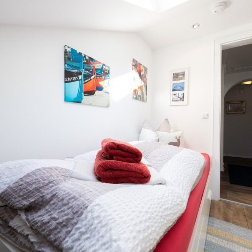 Einzelbett mit rotem Bettbezug in Ferienwohnung in Garmisch-Partenkirchen