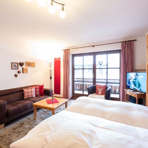 Doppelbett mit großen Fenstern und Gardienen in Ferienwohnung in Garmisch-Partenkirchen