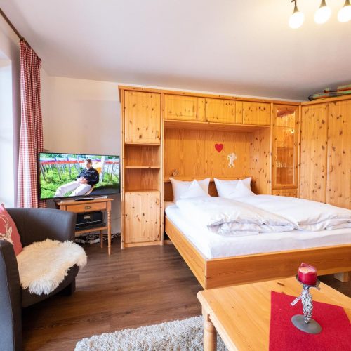 Doppelbett mit Fernseher und Sessel in Ferienwohnung in Garmisch-Partenkirchen
