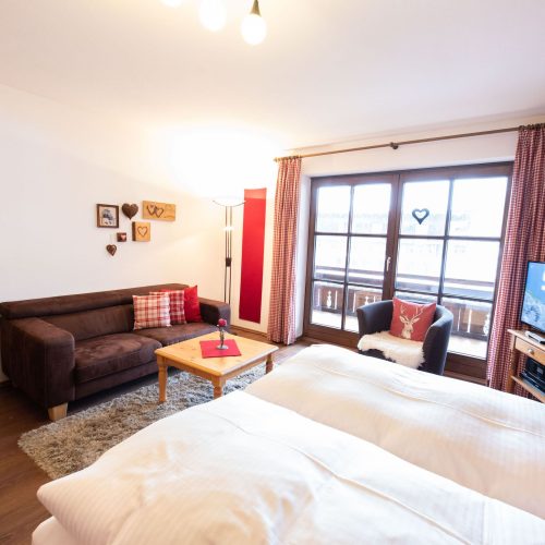 Doppelbett und Sofa mit Fenster in Ferienwohnung in Garmisch-Partenkirchen