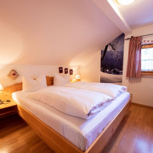 Doppelbett und Fenster in Ferienwohnung in Garmisch-Partenkirchen