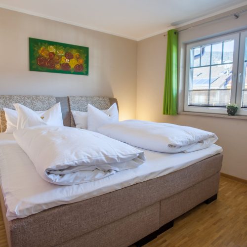 Doppelbett mit grünen Gardienen in Ferienwohnung in Garmisch-Partenkirchen