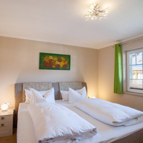 Doppelbett mit Fenster in Ferienwohnung in Garmisch-Partenkirchen