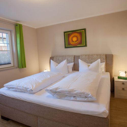 Doppelbett mit Bild und Nachttisch in Ferienwohnung in Garmisch-Partenkirchen