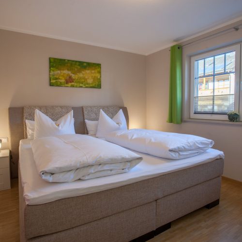 Doppelbett mit grünen Vorhängen in Ferienwohnung in Garmisch-Partenkirchen