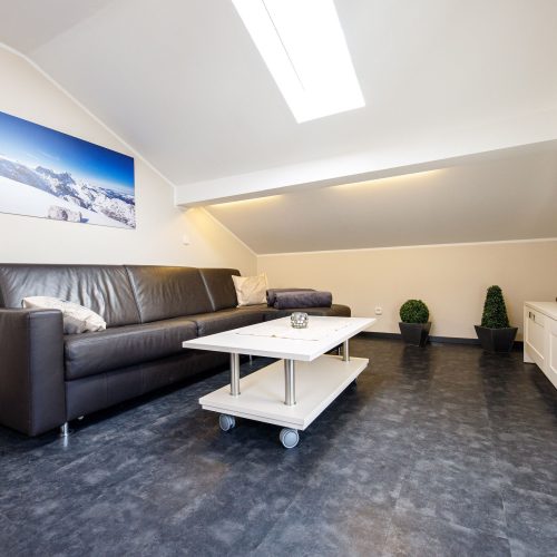 Wohnzimmer mit schwarzem Sofa und weißem Couchtisch in Ferienwohnung in Garmisch-Partenkirchen