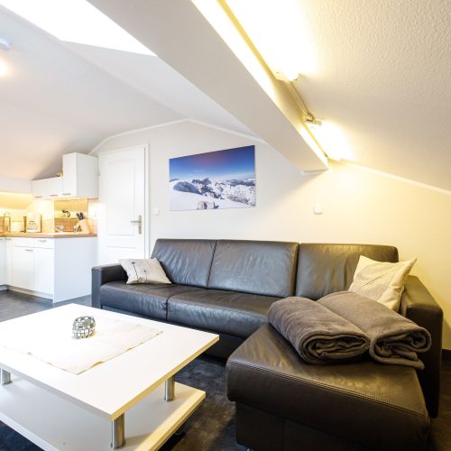 Wohnzimmer mit schwarzem Sofa und weißem Couchtisch in Ferienwohnung in Garmisch-Partenkirchen