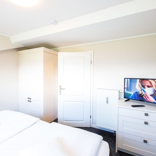 Doppelbett mit Kommode und Fernseher in Ferienwohnung in Garmisch-Partenkirchen