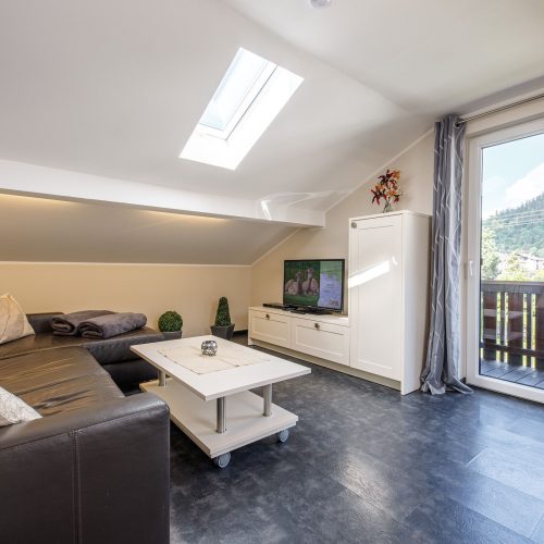 Wohnzimmer mit schwarzem Sofa und Fernseher in Ferienwohnung in Garmisch-Partenkirchen