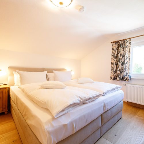 Doppelbett mit großem Fenster in Ferienwohnung in Garmisch-Partenkirchen