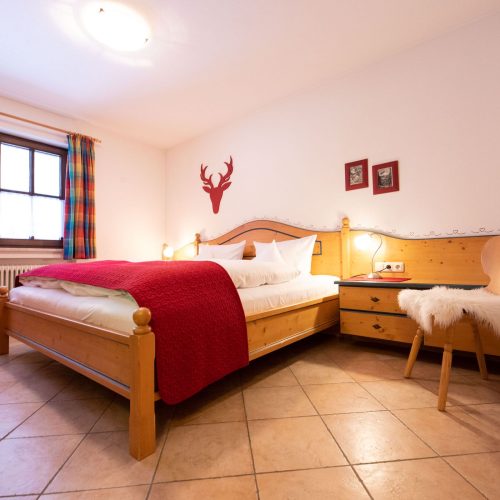 Doppelbett mit Stuhl in Ferienwohnung in Garmisch-Partenkirchen