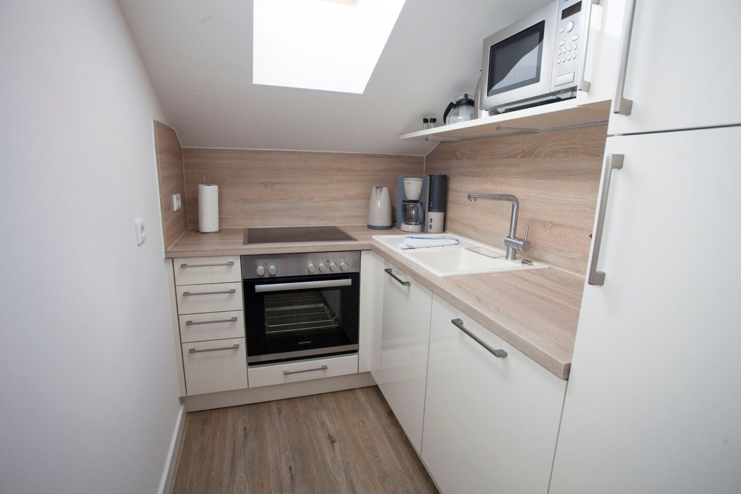 kleine Küche mit Herd und Ofen und einer hellen Holz-Optik Arbeitsfläche in Ferienwohnung in Garmisch-Partenkirchen