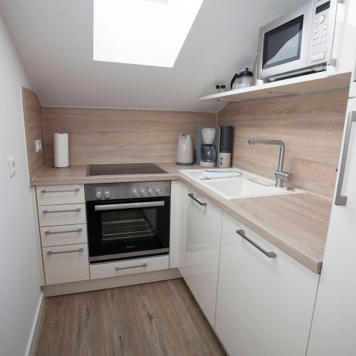 kleine Küche mit Herd und Ofen und einer hellen Holz-Optik Arbeitsfläche in Ferienwohnung in Garmisch-Partenkirchen