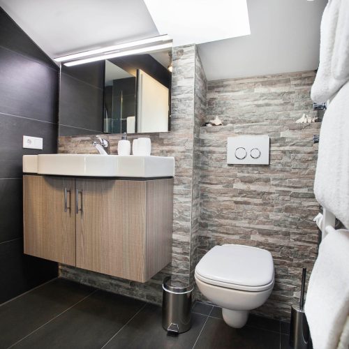 Bad mit einer Stein-Optik Wand und einem Spiegel in Ferienwohnung in Garmisch-Partenkirchen