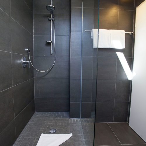 dunkel gefliestes Badezimmer mit einer offenen Dusche in Ferienwohnung in Garmisch-Partenkirchen