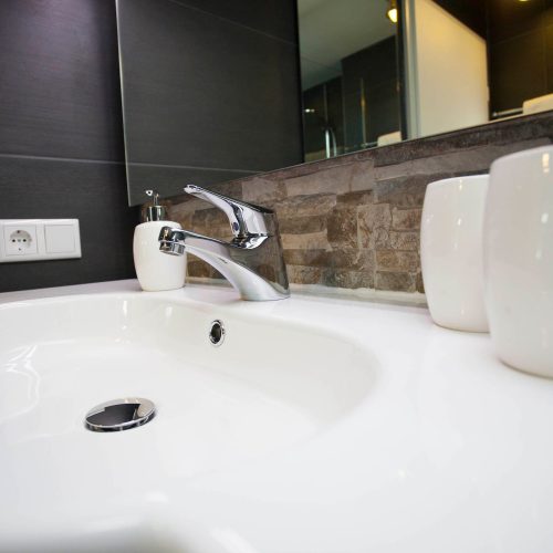 weißes Waschbecken mit einem weißen Seifenspender in Ferienwohnung in Garmisch-Partenkirchen