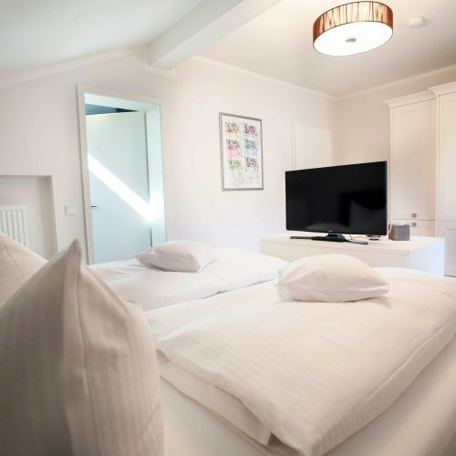 Doppelbettzimmer mit einem Fernseher und einem Kleiderschrank in weiß in Ferienwohnung in Garmisch-Partenkirchen