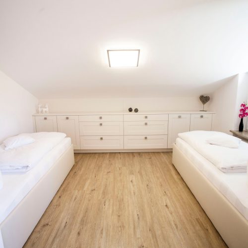 zwei Einzelbetten mit einer langen Kommode und Dekoration in Ferienwohnung in Garmisch-Partenkirchen