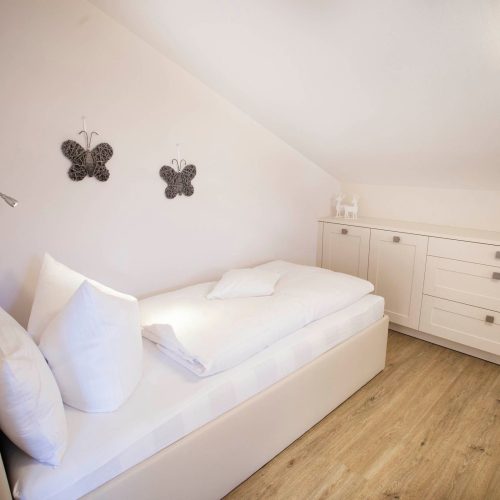 weißes Einzelbett mit einer Kommode in Ferienwohnung in Garmisch-Partenkirchen
