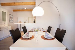 Essbereich mit einem großen weißen Tisch und schwarzen Stühlen in Ferienwohnung in Garmisch-Partenkirchen