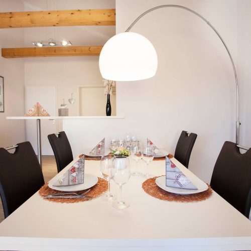 Essbereich mit einem großen weißen Tisch und schwarzen Stühlen in Ferienwohnung in Garmisch-Partenkirchen