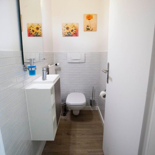 Badezimmer mit einem kleinen Waschbecken und einem großen Spiegel in Ferienwohnung in Garmisch-Partenkirchen