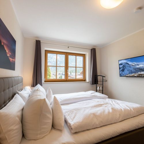 Doppelbett in grau mit Fernseher in Ferienwohnung in Garmisch-Partenkirchen