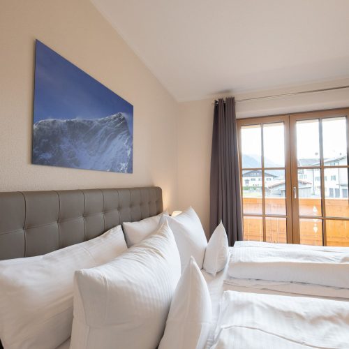Doppelbett mit Fenstern in Ferienwohnung in Garmisch-Partenkirchen
